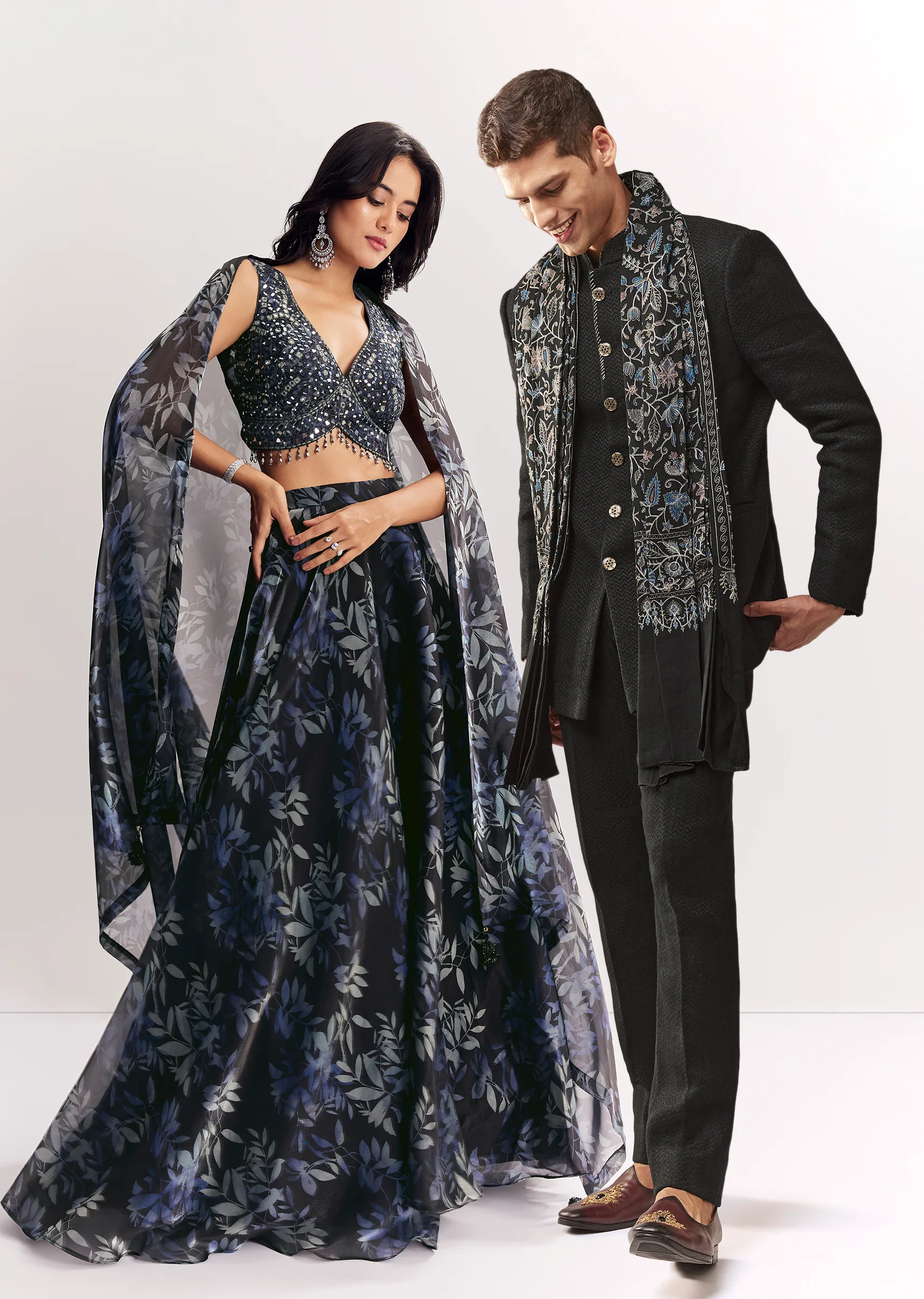 Elegant Festive Couple Set – Black Printed Mirror Work Lehenga Choli In Organza Tissue For Her And Black Matka Silk Jodhpuri Set With Mandarin Collar For Him